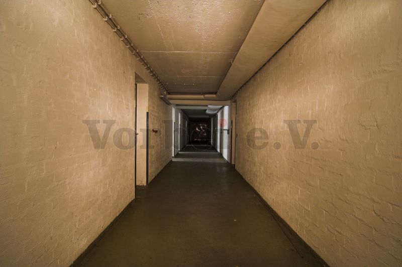 Der Kellermittelgang erstreckt über die gesamte Gebäudelänge. Das Unterkunftsgebäude steht in direkter Nachbarschaft zum Bunker.
