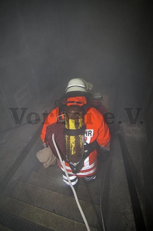 Feuerwehr-Einsatzkräfte begeben sich unter Atemschutz in das vernebelte Fernmeldebetriebsgebäude.