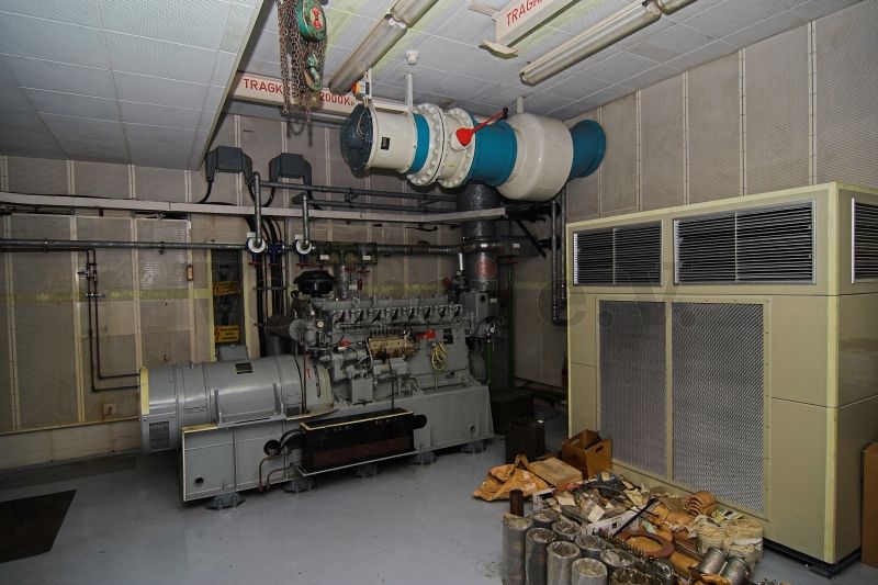 Netzersatzanlage (NEA), Abluftgebläse und Raumkühlgerät im Raum 20. Unter der Raumdecke befinden sich die geforderten Hebezeuge auf Laufschienen.