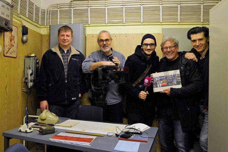 Gruppenfoto im Dienstraum des Bunkerwartes (von links): Vereinsmitglied des Vorbei e.V., SAT.1-Filmteam, Fotograf Marc Theis (mit Buch), Journalist Zoran Pantic.