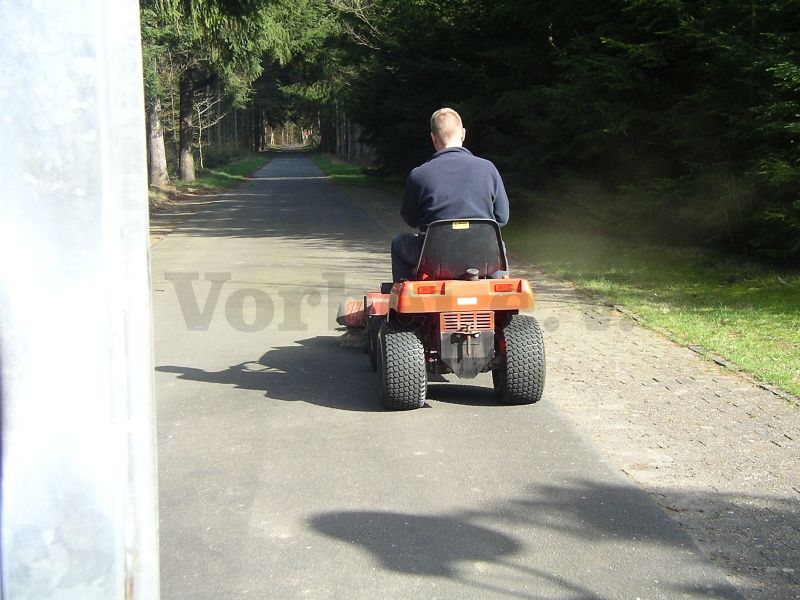 Reinigung der GSVBw-Zufahrtsstraße mit Traktor und Kehrbürste.