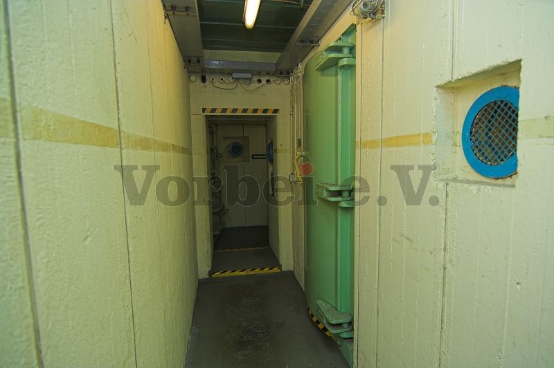 Blick vom Zugang des Eingangsflures (Raum 40) in den Vorraum der Dekontaminationsanlage. Die geöffnete Panzerdrucktür führt in die Schleuse (Raum 52). An der rechten Seite befindet sich die geschlossene Schleusentür zum Auskleideraum der Dekontaminationsanlage (Raum 54).