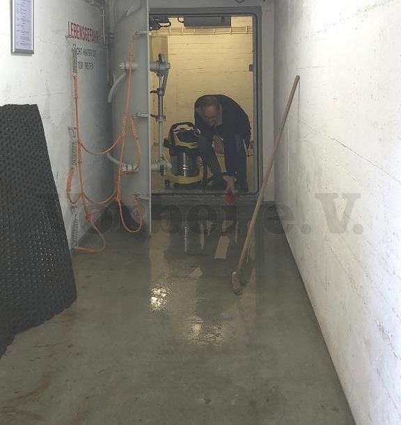 Das Foto zeigt ein Vereinsmitglied des Vorbei e.V. bei der Arbeit mit einem Mehrzwecksauger. Mit Hilfe des Mehrzwecksaugers wird das eingedrungene Wasser aus dem Schleusenvorraum des Bunkers entfernt.