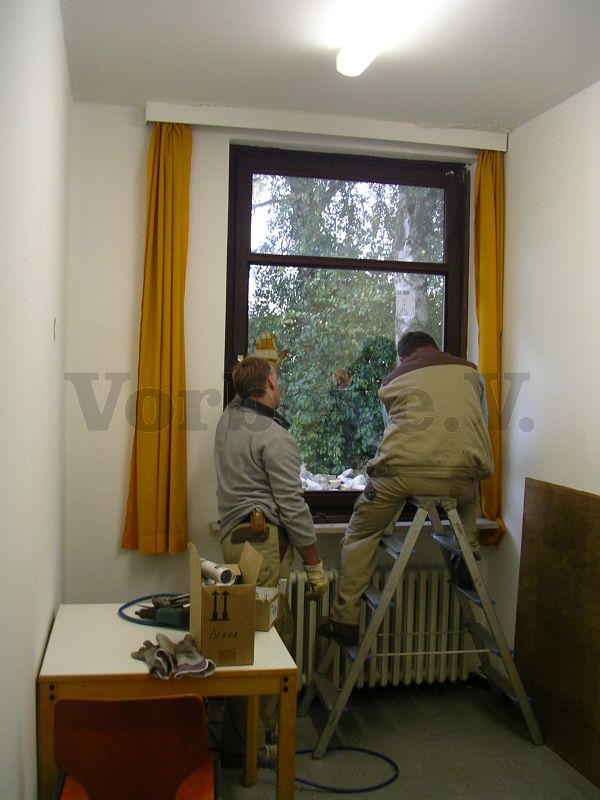 Handwerker beim Austausch der defekten Fensterscheiben im Unterkunftsgebäude (Objekt 2). Die Fensteröffnungen wurden zuvor provisorisch mit Holzplatten verschlossen.