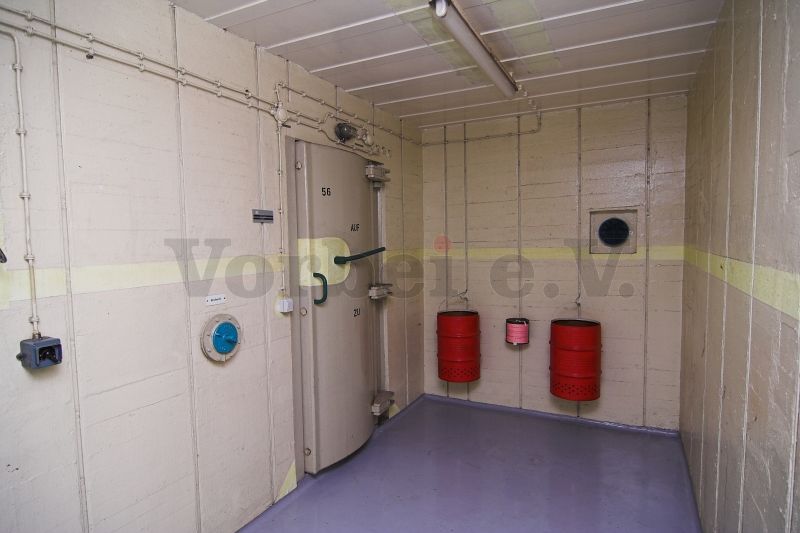 Durchgang in den Duschraum (Raum 56). Die roten Metalltonnen dienen zum Verbrennen von VS-Material. Im mittleren Behälter befindet sich eine Verbrennungsflüssigkeit.