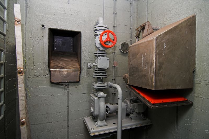 Im Raum 55: Links befindet sich die Kleiderrutsche aus dem Duschraum (Raum 56) und rechts endet die Kleiderrutsche aus dem Auskleideraum (Raum 54). Die Pumpe befördert kontaminiertes Wasser in das Objekt 7 (Auffang- und Absetzgrube).