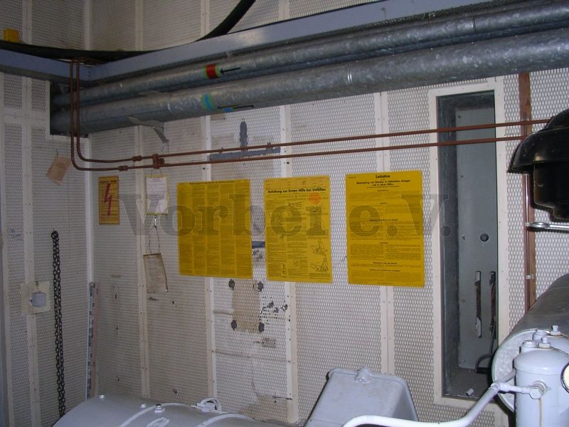 Hinweistafeln für elektrische Betriebsräume an der Wand hinter dem NEA-Generator im Raum 20.