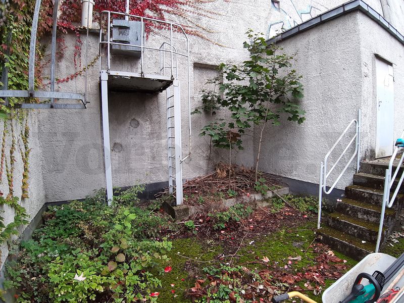 Das Foto zeigt die Zerschellerplatte auf der Bunkerrückseite, mit Moos und Pflanzenbewuchs nahezu vollständig bedeckt ist. Auf der rechten Bildseite sind die Versorgungsräume zu sehen. Der Zugang zu diesen Räumen ist nur von außen möglich, weil keine Verbindung zum Bunker besteht.