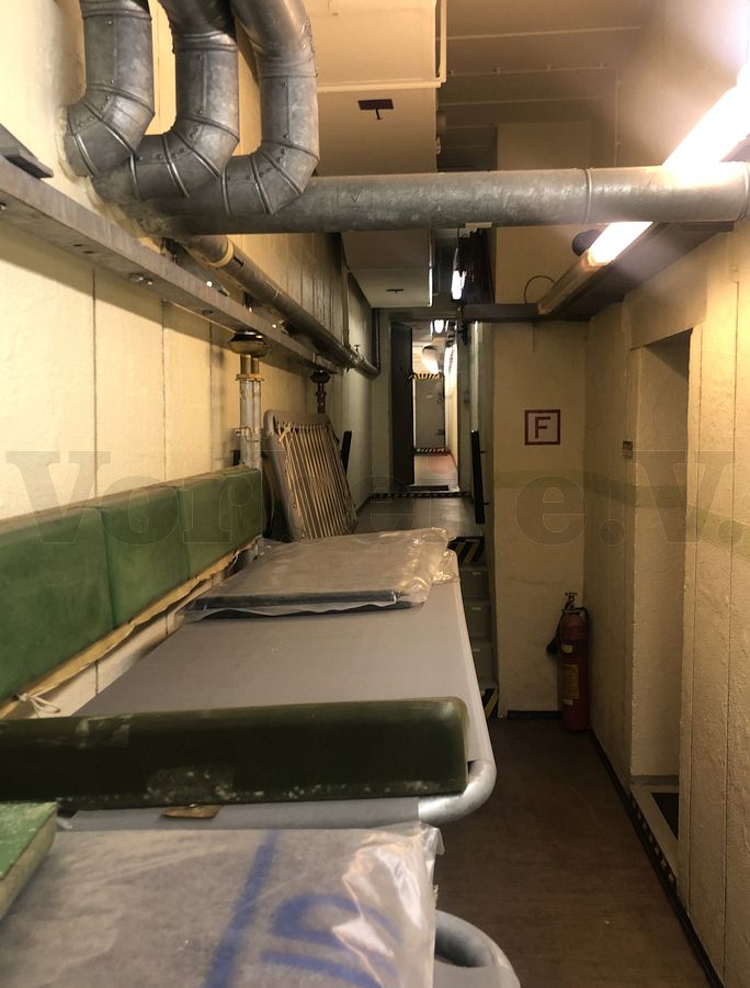 Dieser Bereich im Bunker wird als Flur mit Ruhemöglichkeit (Raum 41) bezeichnet. An der Wand befinden sich insgesamt 12 hochklappbare Schutzraumliegen. Auf der rechten Seite befindet sich der Zugang zur Notküche (Raum 33).