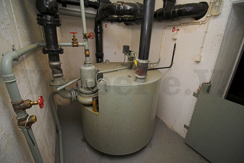 Auf dieser Aufnahme ist zu erkennen, dass die Abwasserhebeanlage in einem abgesetzten Maschinenraum untergebracht ist. Mittels einer Schutztür im Zugang (rechte Bildseite) wird der Bunker vor auslaufenden Abwässern geschützt.