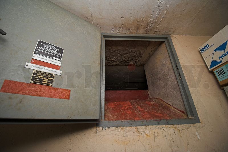 Die Wartungstür zum Tankbehälter zwei im Bunker ist geöffnet. In der Türöffnung ist die Oberkante des Tankbehälters zu erkennen. Etwa 50cm darüber beginnt bereits die Raumdecke. Dieser schmale Bereich dient als Arbeitsbereich für Wartungsarbeiten.