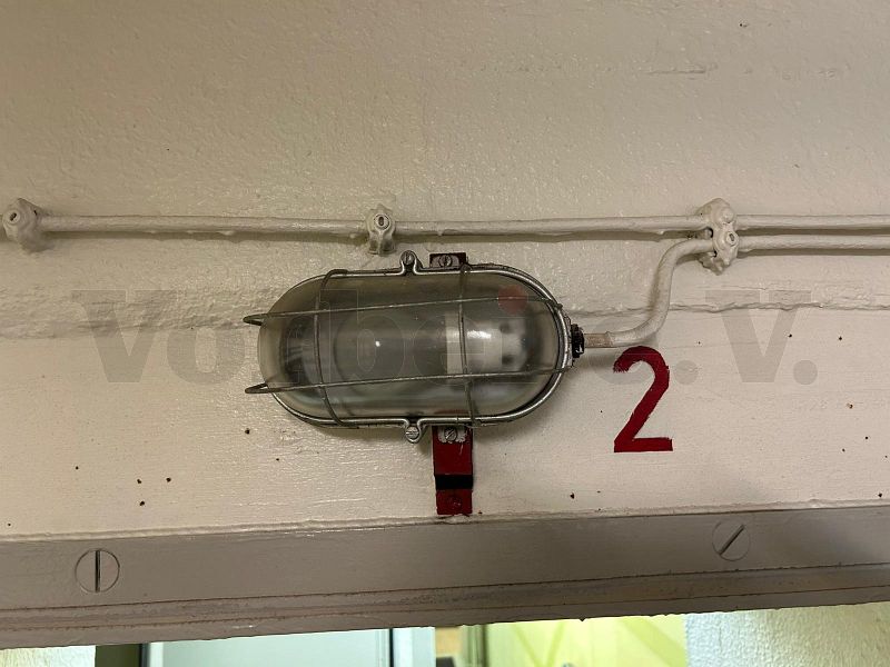 Eine Notbeleuchtungslampe über dem Zugang zum Raum 43 (Verbindungsflur) wurde mit einer roten „2“ rechts neben der Lampe beschriftet. Daher ist diese Lampe dem Notbeleuchtungskreis 2 zuzuordnen.