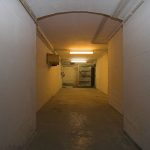 Schleusenraum der Schleuse Nr.6 im Museumsbunker Hannover. Im hinteren Bereich befindet sich die hydraulisch betätigte innere Schleusentür, die in den Bunker führt. Links daneben, mit einer Schutzfolie abgedeckt, befindet sich die Dekontaminationsdusche.