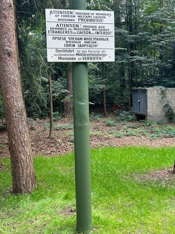 In den ursprünglichen Zustand der 1960er-Jahre zurückversetzt: der Mast mit einem originalen Hinweisschild, das die Durchfahrt für Militärmissionen untersagt – in den Landessprachen der Siegermächte. Der Mast präsentiert sich wieder so, wie in den 1960er-Jahren: Mit einem originalen Schild, das Militärmissionen die Weiterfahrt verbot – beschriftet in den Sprachen der Siegermächte.