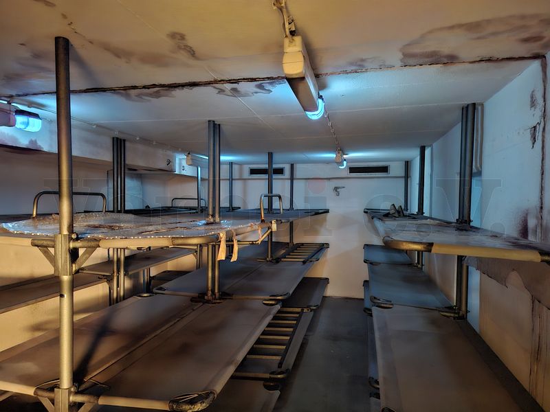 In diesem Liegeraum wurden die oberen Ebenen der Schutzraumliegen an besonders betroffenen Stellen mit Folie abgedeckt, um sie vor herabtropfendem Wasser aus dem dar&uuml;berliegenden Obergeschoss zu sch&uuml;tzen.