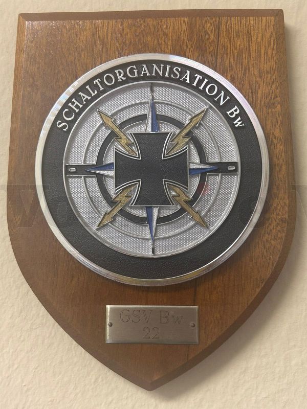 Diese historische Wandtafel zeigt das Organisationsymbol der „Schaltorganisation Bundeswehr“. Die darunter angebrachte Metallplakette trägt die Gravur „GSVBw 22“. Diese historische Wandtafel zeigt das Organisationsymbol der "Schaltorganisation Bundeswehr". Die darunter angebrachte Metallplakette trägt die Gravur "GSVBw 22".